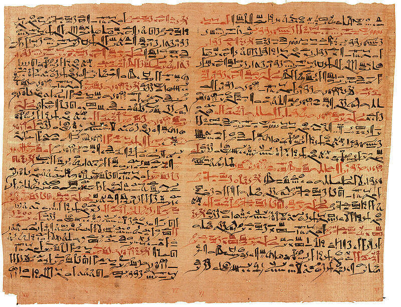 Fotografia. Papiro Edwin Smith de formato retangular, fundo bege alaranjado e extremidades desgastadas. Texto em escrita hierática nas cores preto e laranja.