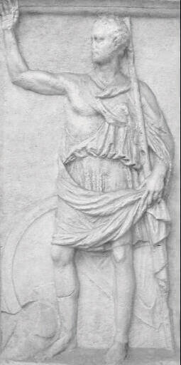 Fotografia de escultura em mármore cinza claro. Homem adulto em pé, de cabelo curto. Usa um manto enrolado no braço esquerdo e na cintura. A mão esquerda segura o manto da cintura e uma lança. O braço direito está levantado em posição de aceno.